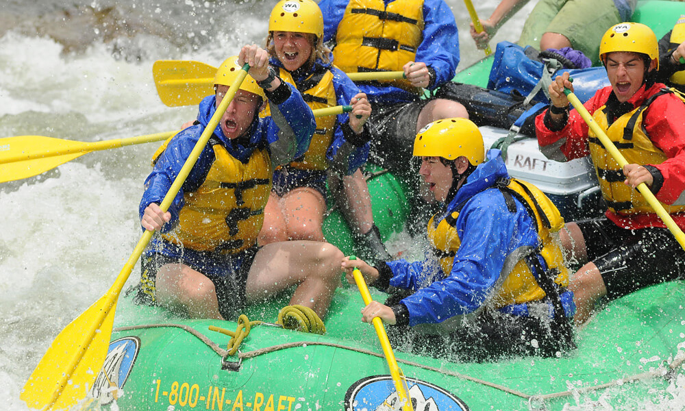 Group of rafters navigating intense white water rapids on the Arkansas River during a Browns Canyon rafting trip in Colorado.