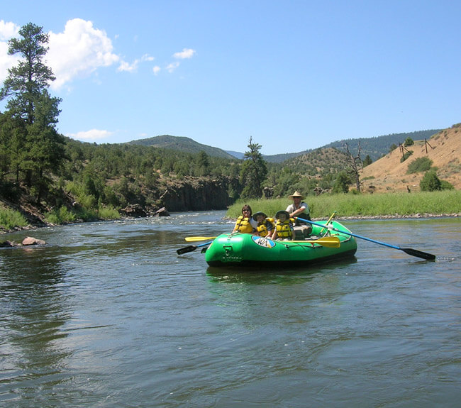 two kids and two adults enjoy a day on the river on a green raft