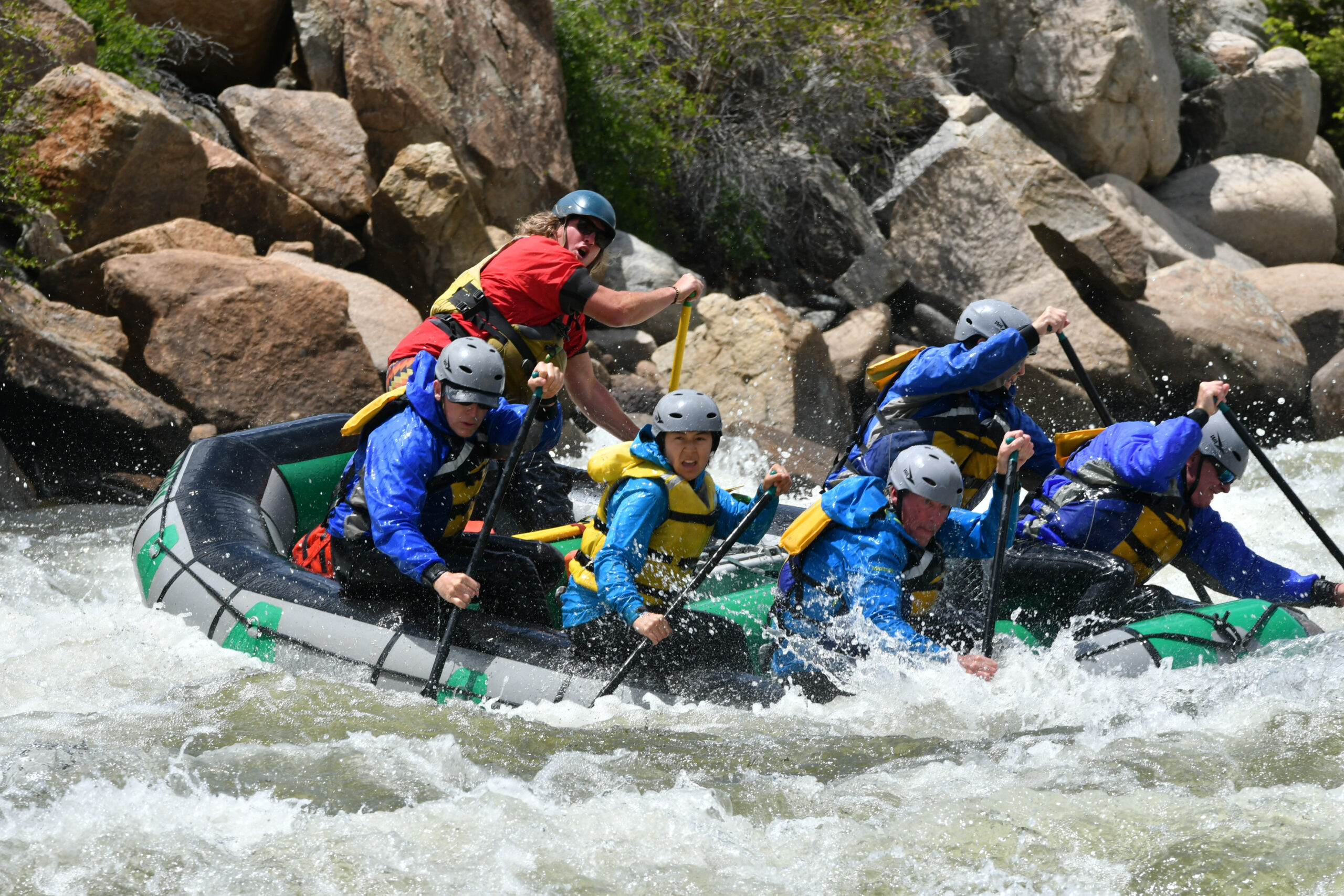 A river guide shouts commands at the passengers in his boat