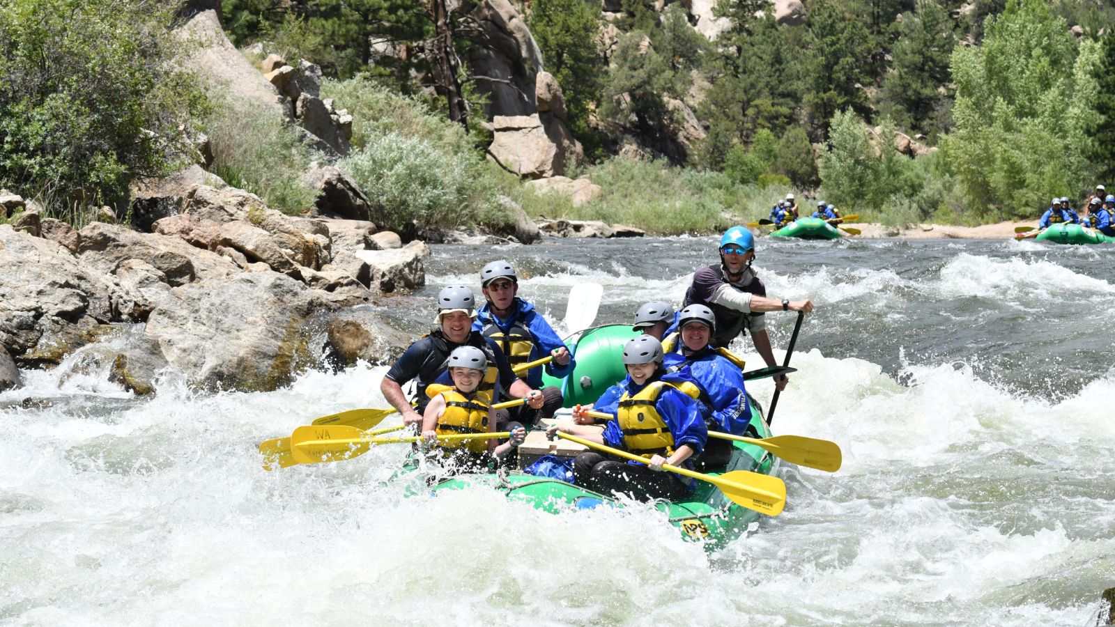 people white water rafting in a green raft