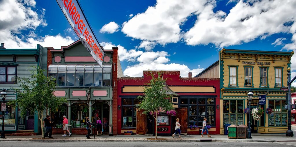 People walk through a quaint town in Colorado amongst blue skies and clouds