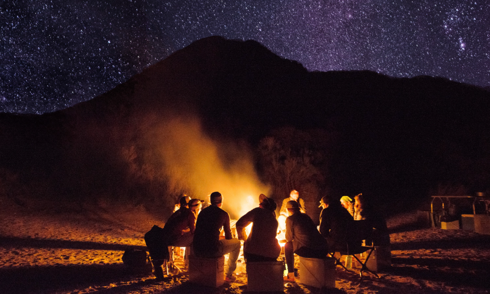 a group of people sit around a fire