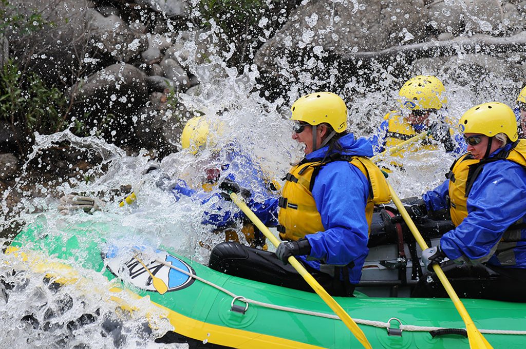 A group of people in a raft hitting a large wave while rafting in Colordao