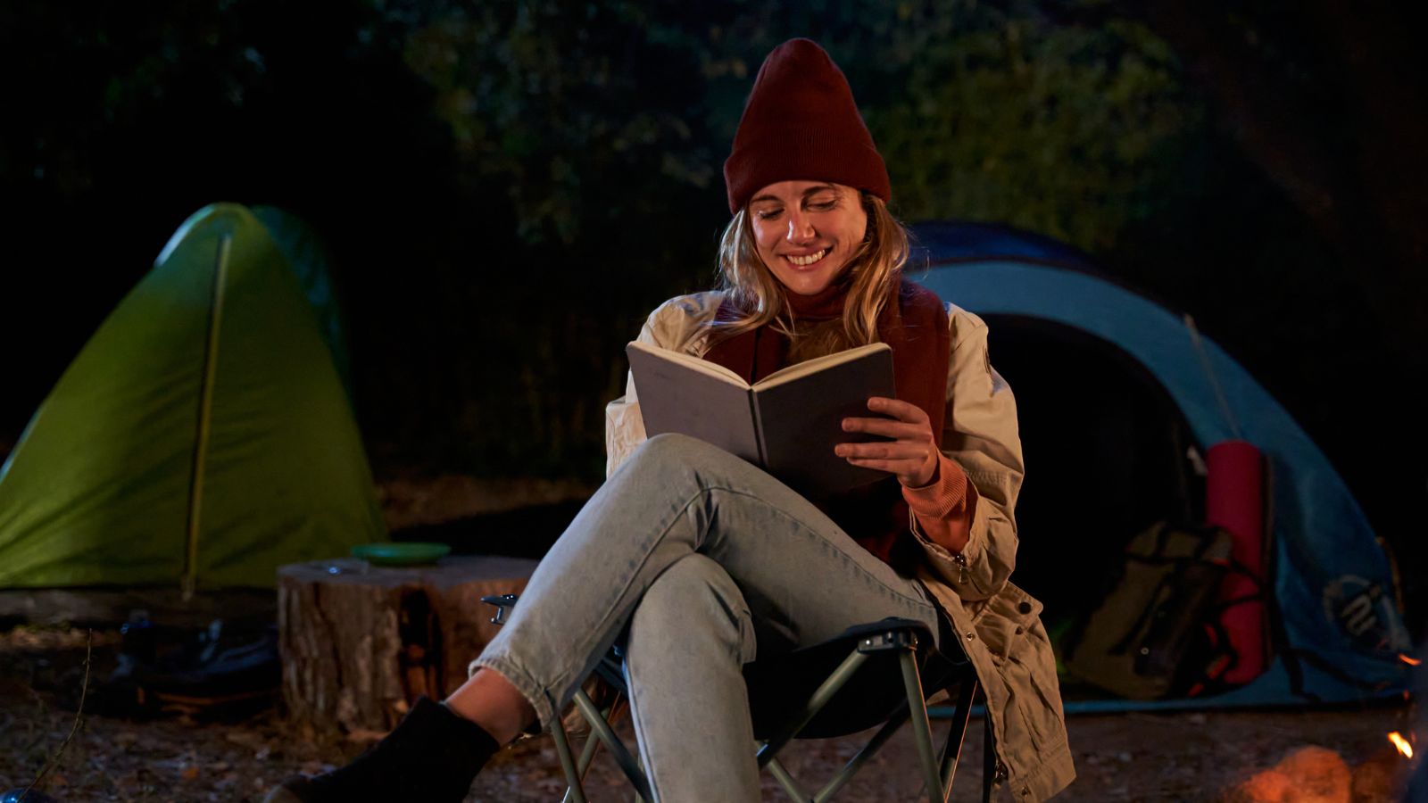 A woman reading a book while camping