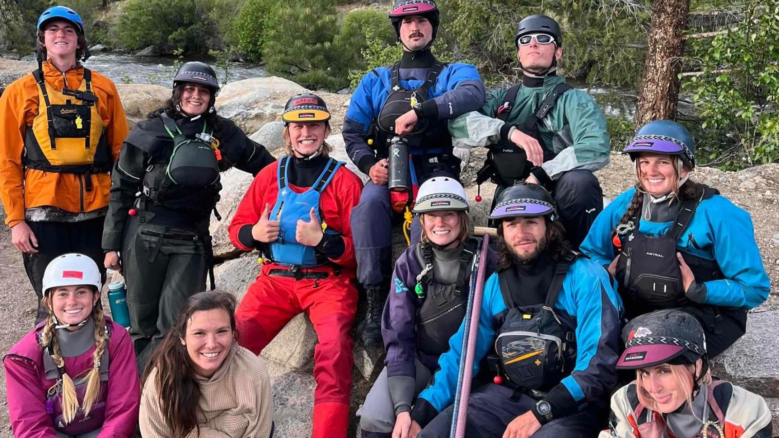 Guides in rafting gear sitting on rocks next to the river